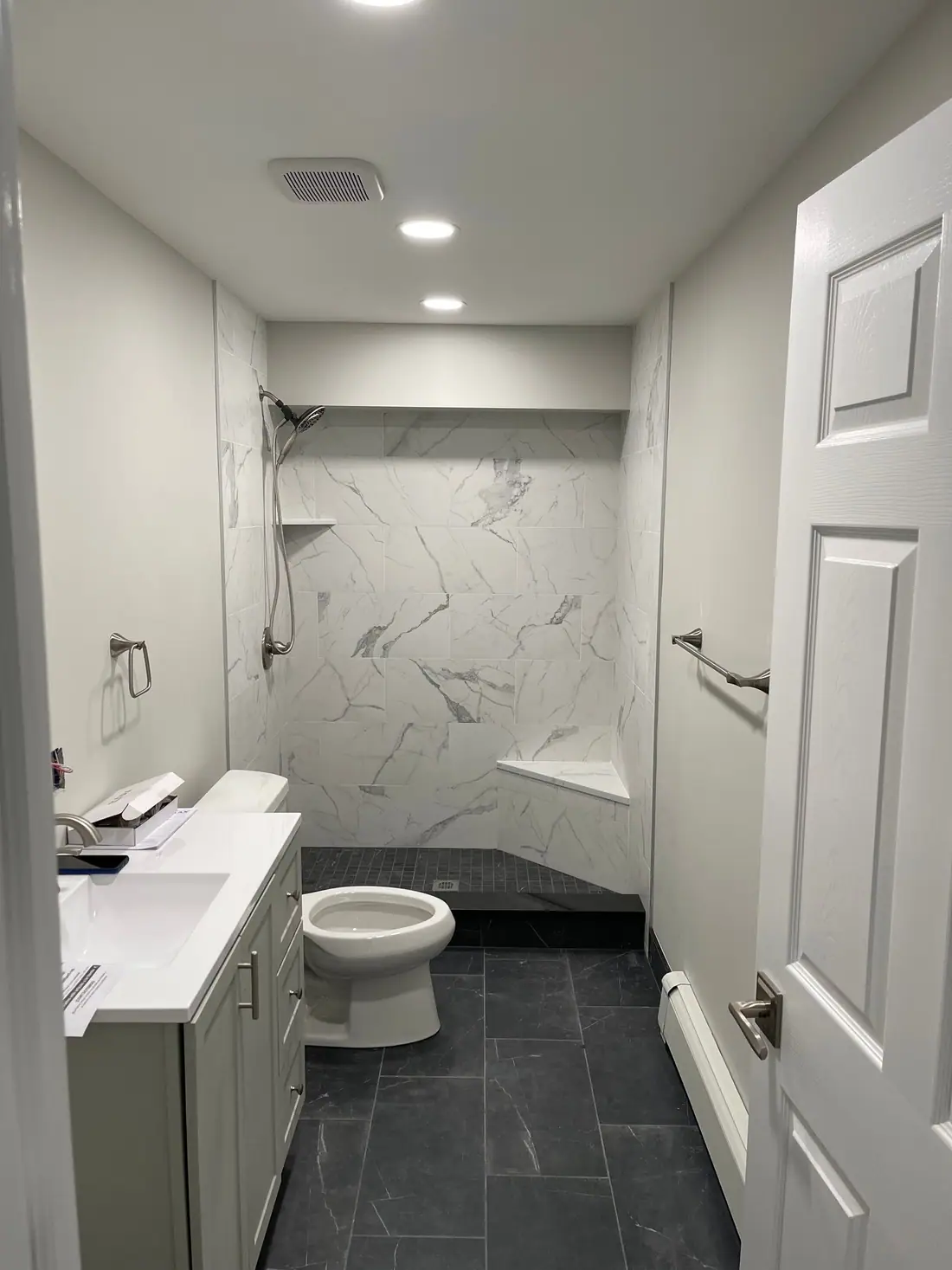 Marble-look tile shower and dark tile floor