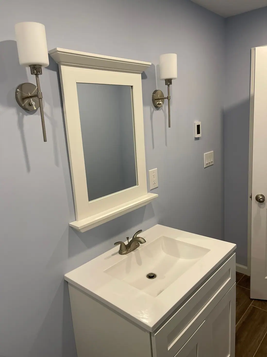 White vanity with a framed mirror and sconces