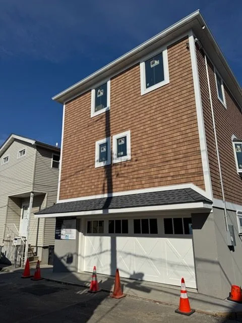 Finished new build with shingle siding and a carriage-style garage door