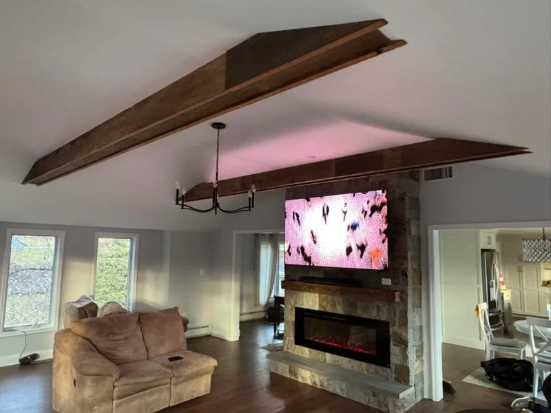 Rough-sawn ceiling beams over a stone fireplace wall