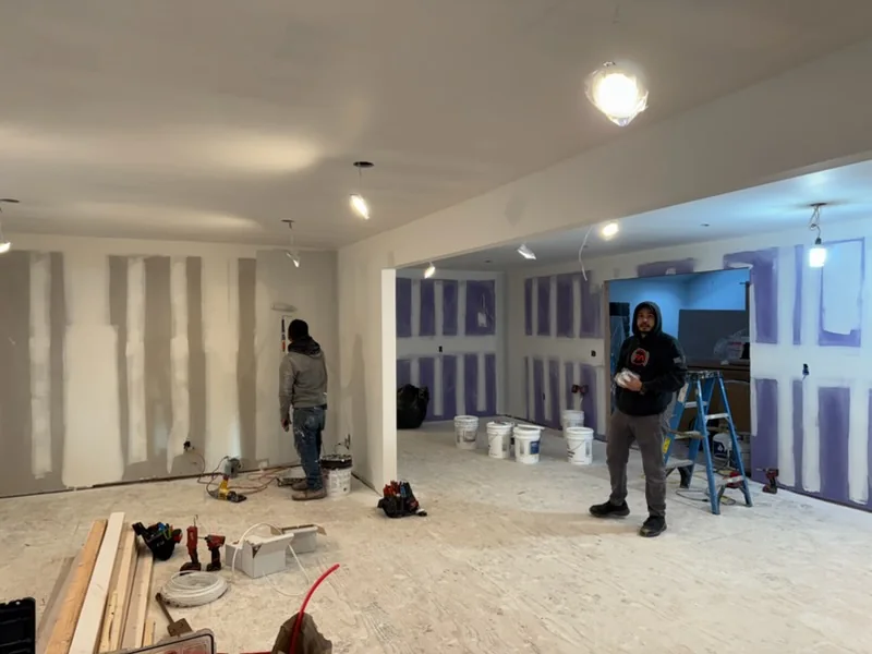 Crew hanging drywall across an open floor