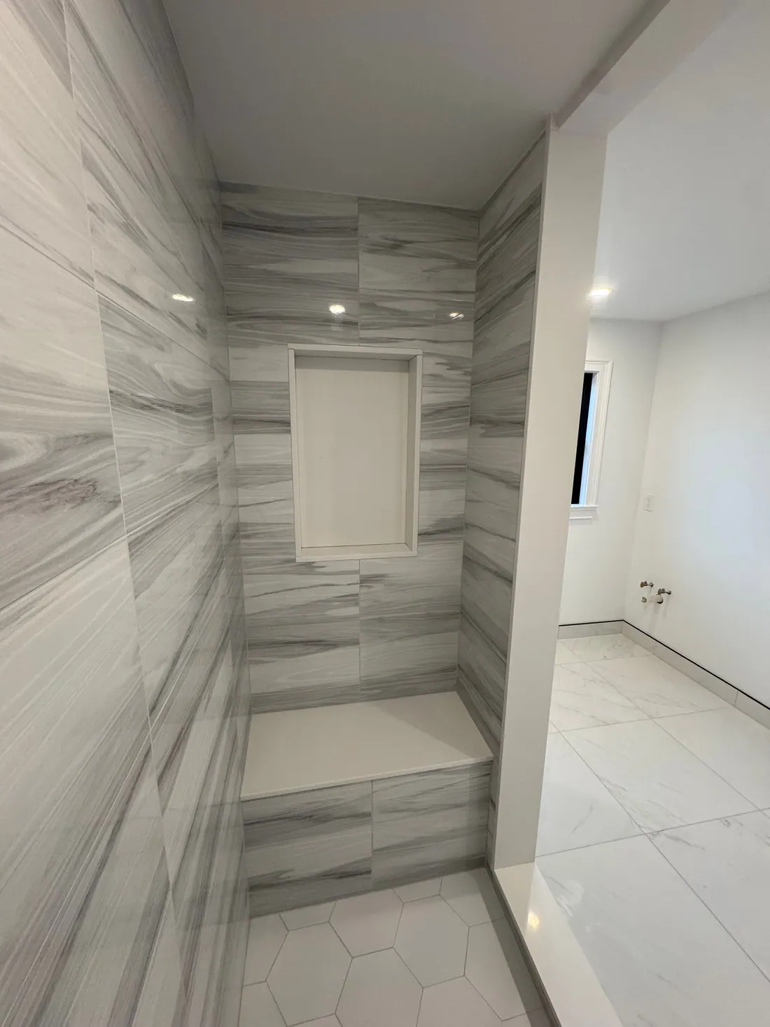 Walk-in shower beside a marble-look floor